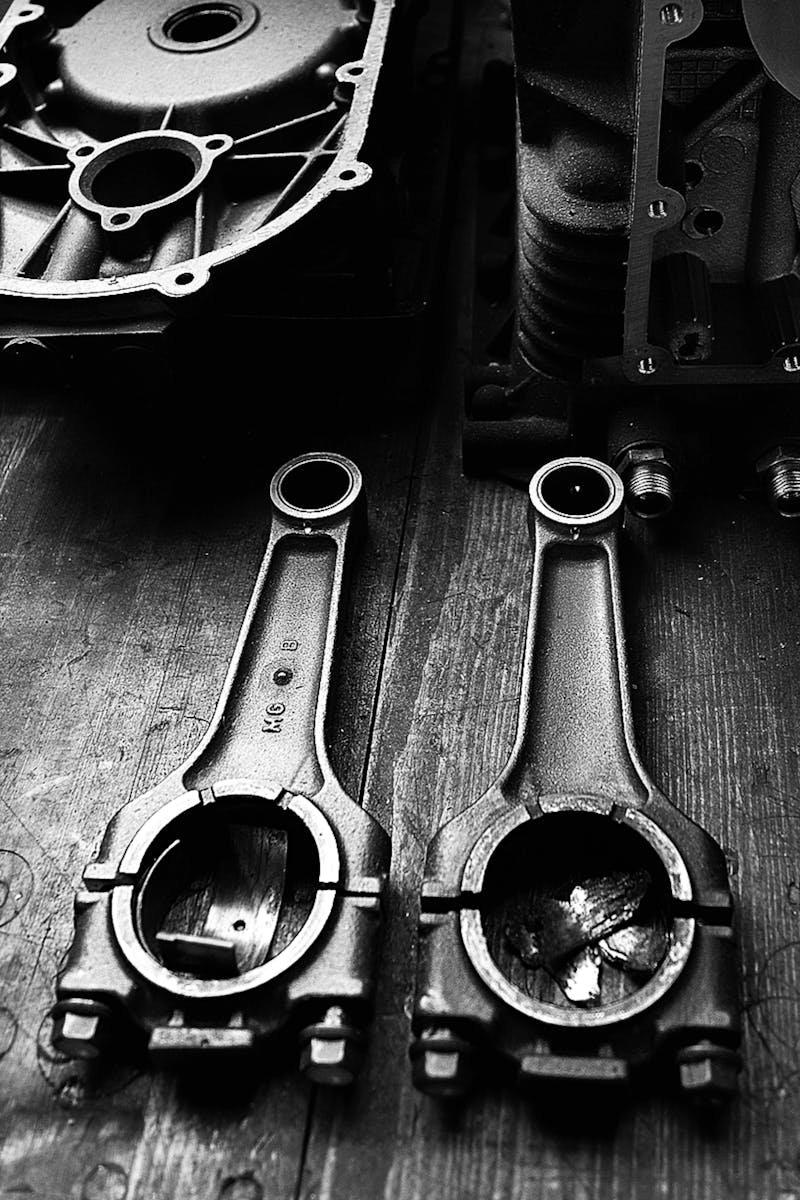 Monochrome close-up of metal engine parts on a wooden surface, showcasing industrial design.